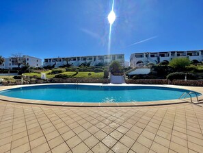 A swimming pool with a stone border, surrounded by a tiled patio.