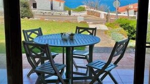 Una mesa redonda con cuatro sillas en un patio con vista al mar y edificios.