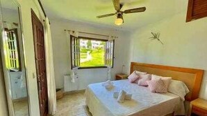 Un dormitorio con cama, ventilador de techo, ventana y puerta.