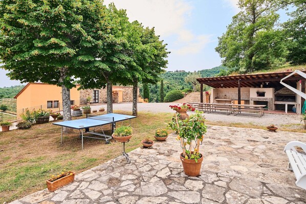 An outdoor patio with a ping pong table, potted plants, and a stone floor. - Tranquil Chianti Escape for 4 (Cavriglia)