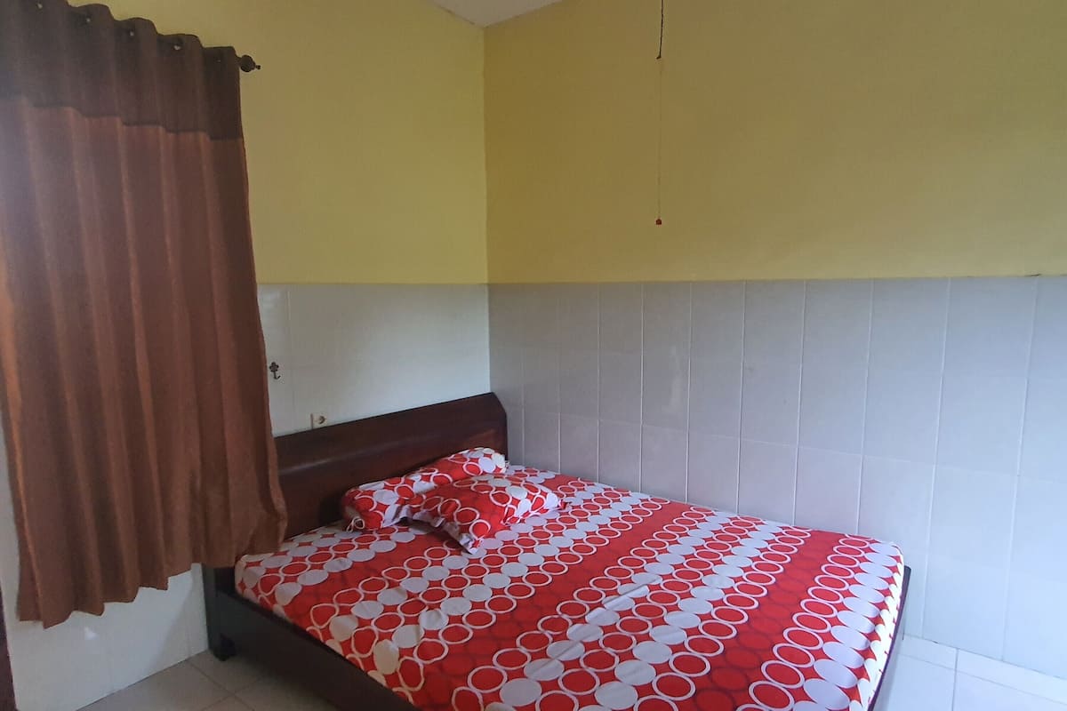 A bedroom with a bed, brown curtains, and a yellow wall.