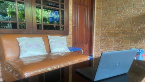 A room with a leather sofa, a laptop on a table, and a wooden door. - Hotel O Damia Homestay Syariah (Surabaya)