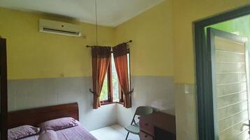 A room with a bed, a desk, and an air conditioning unit on the wall.