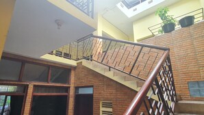 A multi-level interior with a staircase, brick walls, and a balcony with potted plants. - Hotel O Damia Homestay Syariah (Surabaya)
