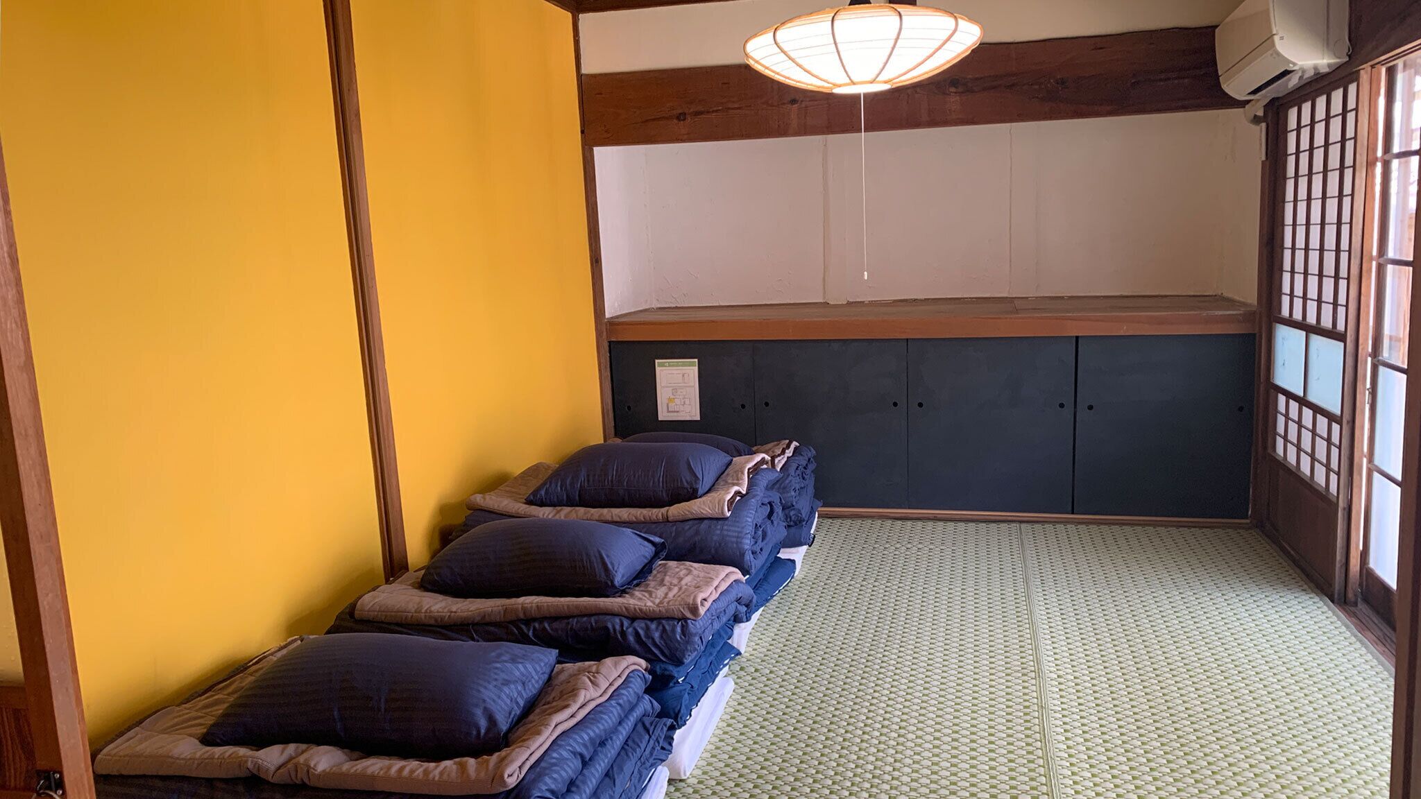 Une pièce de style japonais traditionnel, avec un sol recouvert de tatamis, un plafond bas en bois et une porte coulissante de type shoji.