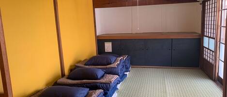 Une pièce de style japonais traditionnel, avec un sol recouvert de tatamis, un plafond bas en bois et une porte coulissante de type shoji.