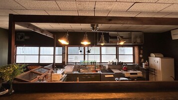 Una cocina con mostrador de madera, luces colgantes, un ventanal con vistas y un refrigerador.