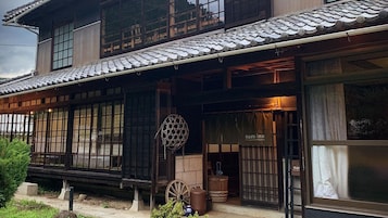 Un edificio japonés tradicional con techo de tejas, ventanas con celosías de madera y un letrero que dice 'nara inn'.