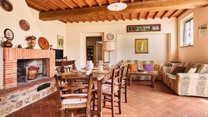 A rustic living room with a brick fireplace, wooden dining table, and a sofa.