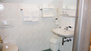 Un baño con inodoro, lavamanos y zona de ducha.