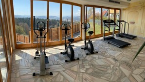 Un gimnasio en casa con equipo de ejercicio y vistas panorámicas a través de amplios ventanales.