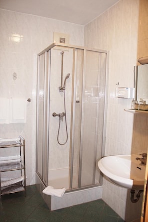 A shower enclosure with a glass door, a sink with a mirror, and a towel rack.