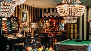 A bar area with a pool table, bar stools, and a variety of bottles and decorations. - De Stobbe hotel & suites (Ruinen)