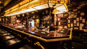 A bar with a long counter, stools, and various bottles and glasses. - De Stobbe hotel & suites (Ruinen)