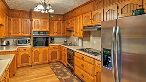Una cocina con armarios de madera, electrodomésticos de acero inoxidable y piso de damasco.
