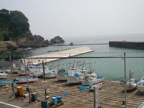 A marina with boats docked, a rocky coastline, and a pier extending into the water. - Tamagawa Onsen Tamashimaso (Echizen)