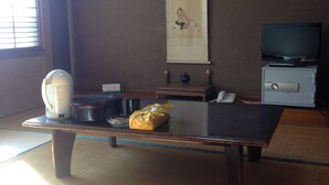 Een traditionele Japanse kamer met tatami vloerbedekking, een lage tafel, een televisietoestel en een grote wandrol.