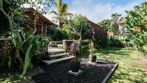 A garden with a stone wall, a wooden pergola, and a potted plant with purple flowers.
