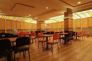 A spacious restaurant with high ceilings, wooden paneling, and a variety of seating options including tables and chairs.