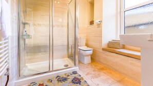 A modern bathroom with a glass shower enclosure, a toilet, and a sink with a mirror.