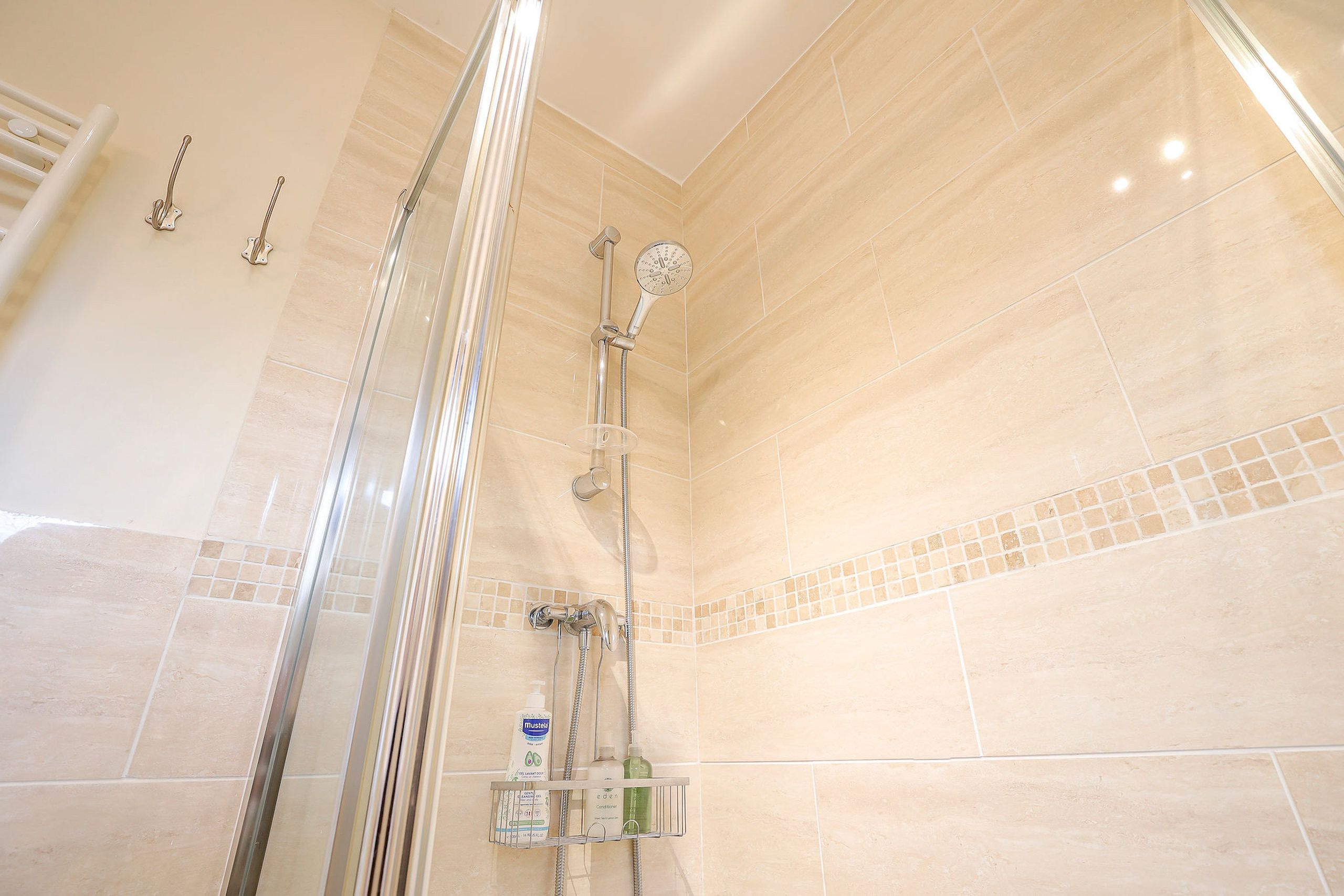 A shower with a glass door, a handheld showerhead, and a handheld shower attachment.