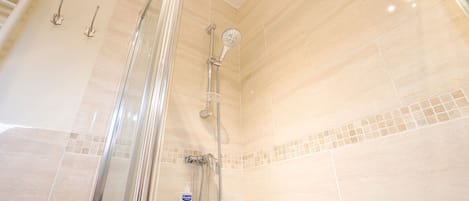 Een douche met een glazen deur, een handdouche en een apart douchehandstuk.