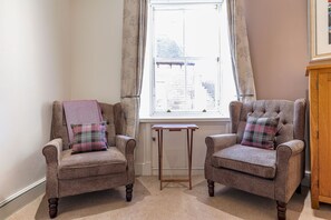 A room with two armchairs, a small table, and a window with curtains. - House On The Harbour | Pittenweem (Pittenweem)