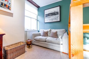 A cozy living room with a light-colored sofa, a wicker basket, and a wooden stool. - House On The Harbour | Pittenweem (Pittenweem)