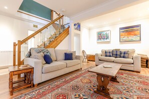 A spacious living room with a staircase, two sofas, a coffee table, and a patterned rug. - House On The Harbour | Pittenweem (Pittenweem)