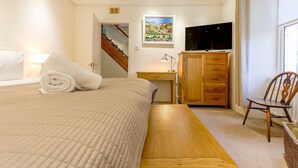 A bedroom with a bed, a desk, a TV, a chair, and a wardrobe.