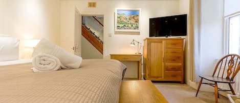 A bedroom with a bed, a desk, a TV, a chair, and a wardrobe.