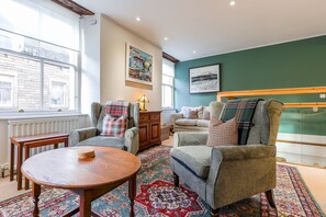 A cozy living room with a large window, a wooden table, and a patterned rug. - House On The Harbour | Pittenweem (Pittenweem)