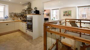 Une cuisine moderne avec des meubles blancs, des appareils en acier inoxydable et un escalier en bois.