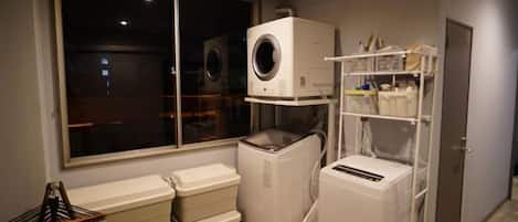 Un cuarto de lavado con lavadora, secadora y contenedores de plástico apilados.