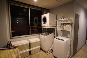 Un cuarto de lavado con lavadora, secadora y contenedores de plástico apilados.