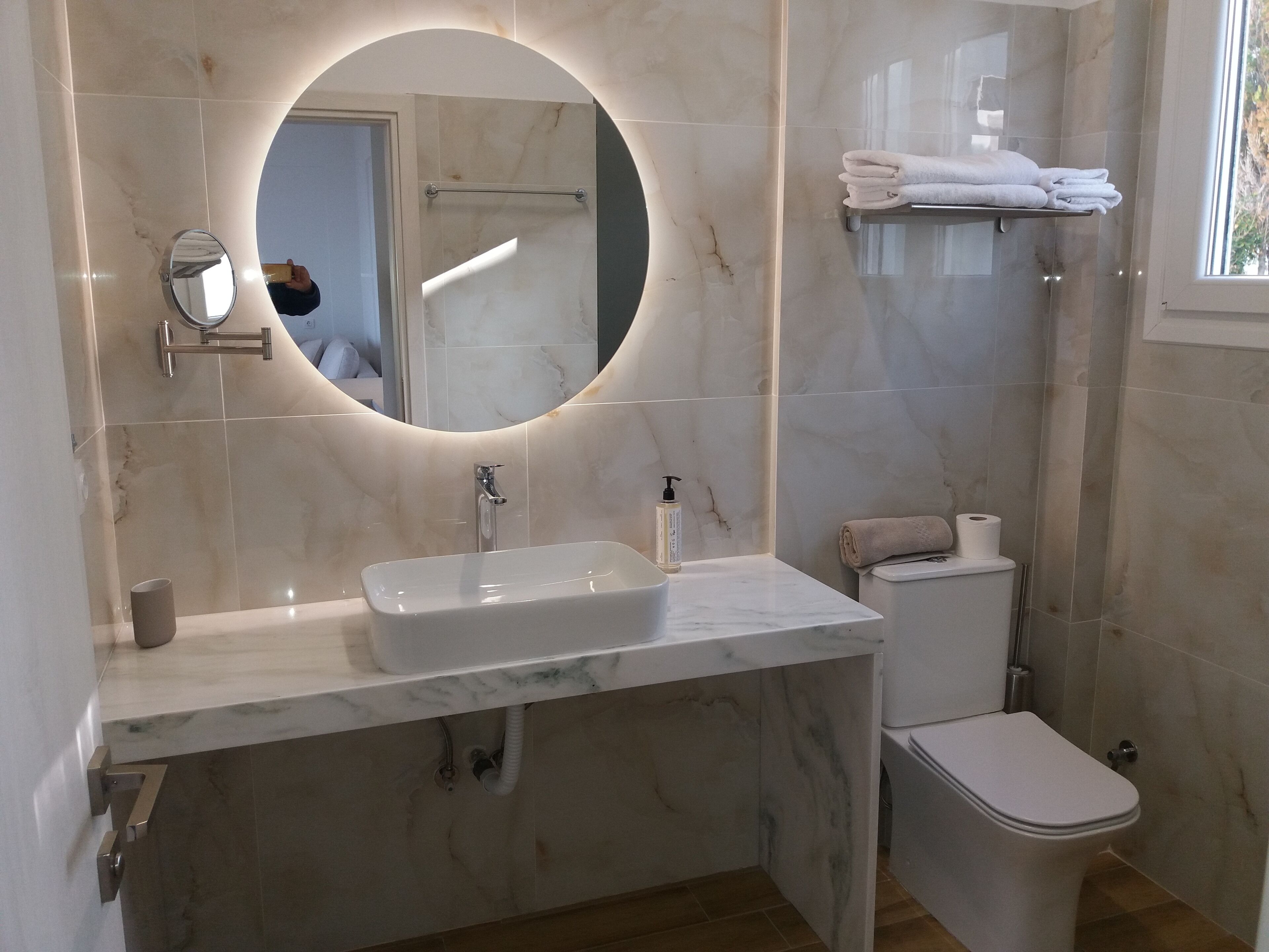 Une salle de bain moderne avec un lavabo en marbre, des toilettes et un porte-serviettes.