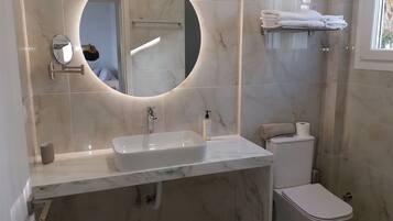 Une salle de bain moderne avec un lavabo en marbre, des toilettes et un porte-serviettes.