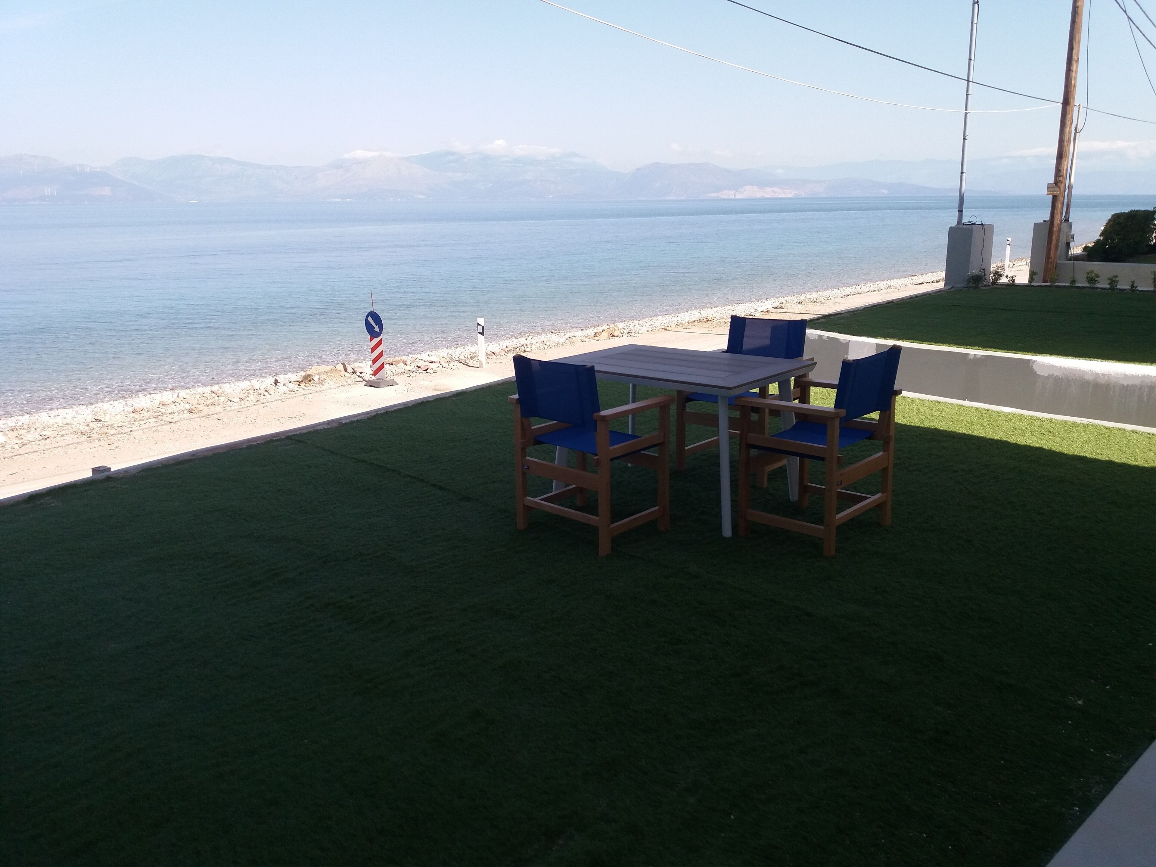 A patio with a table and chairs overlooking a beach.