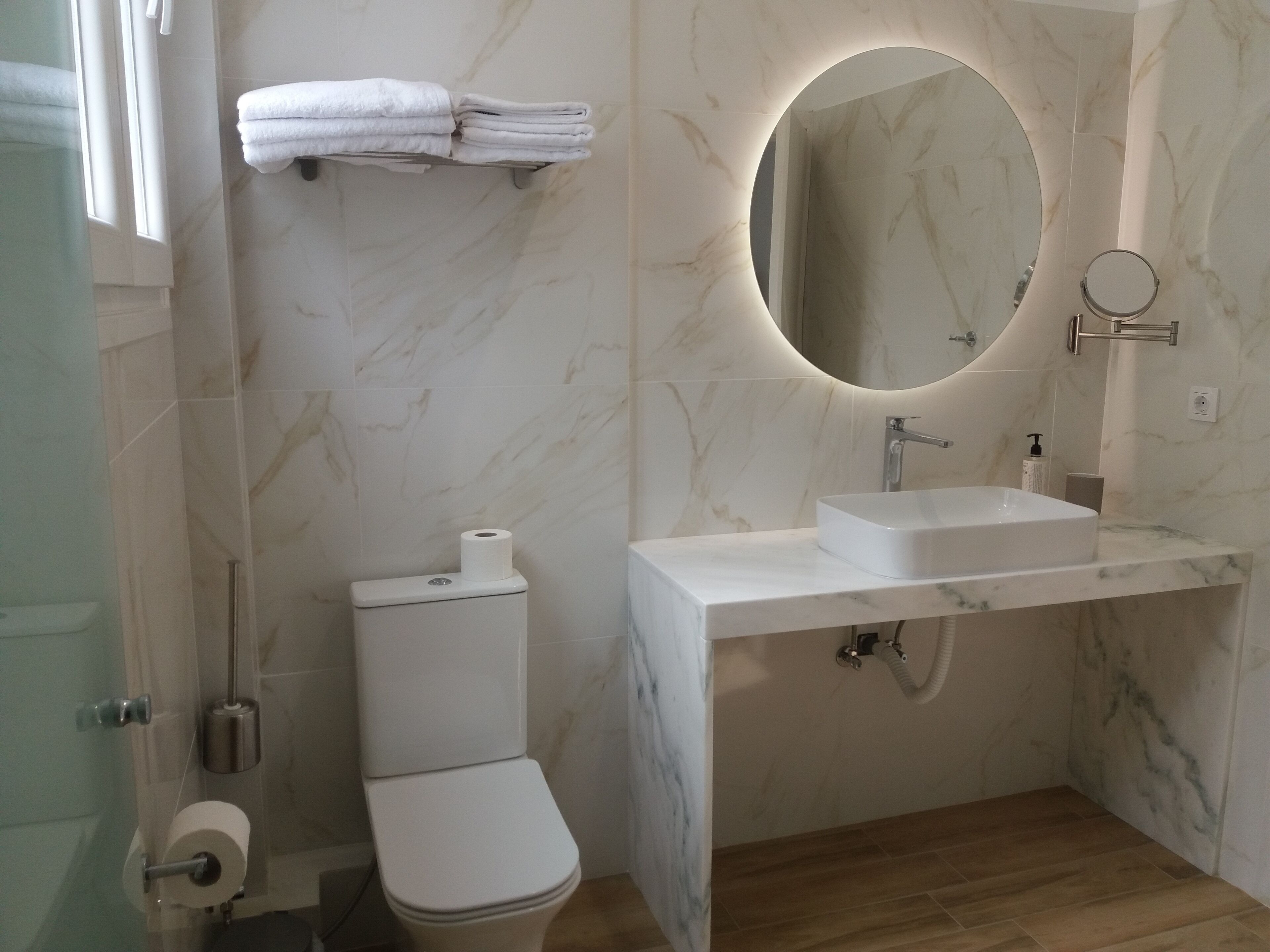 Un baño moderno con inodoro, lavamanos y espejo.