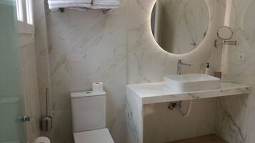 Un baño moderno con inodoro, lavamanos y espejo.