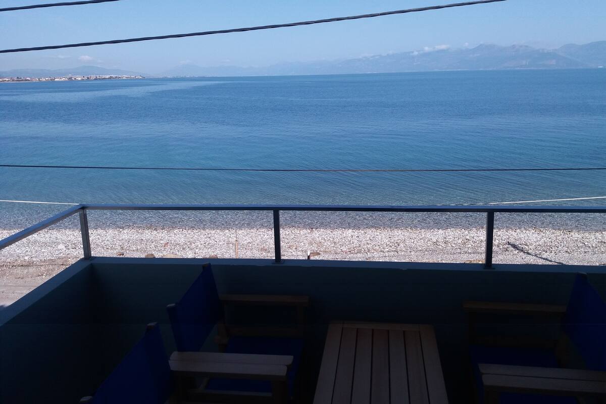 A balcony with a view of the sea and distant mountains.