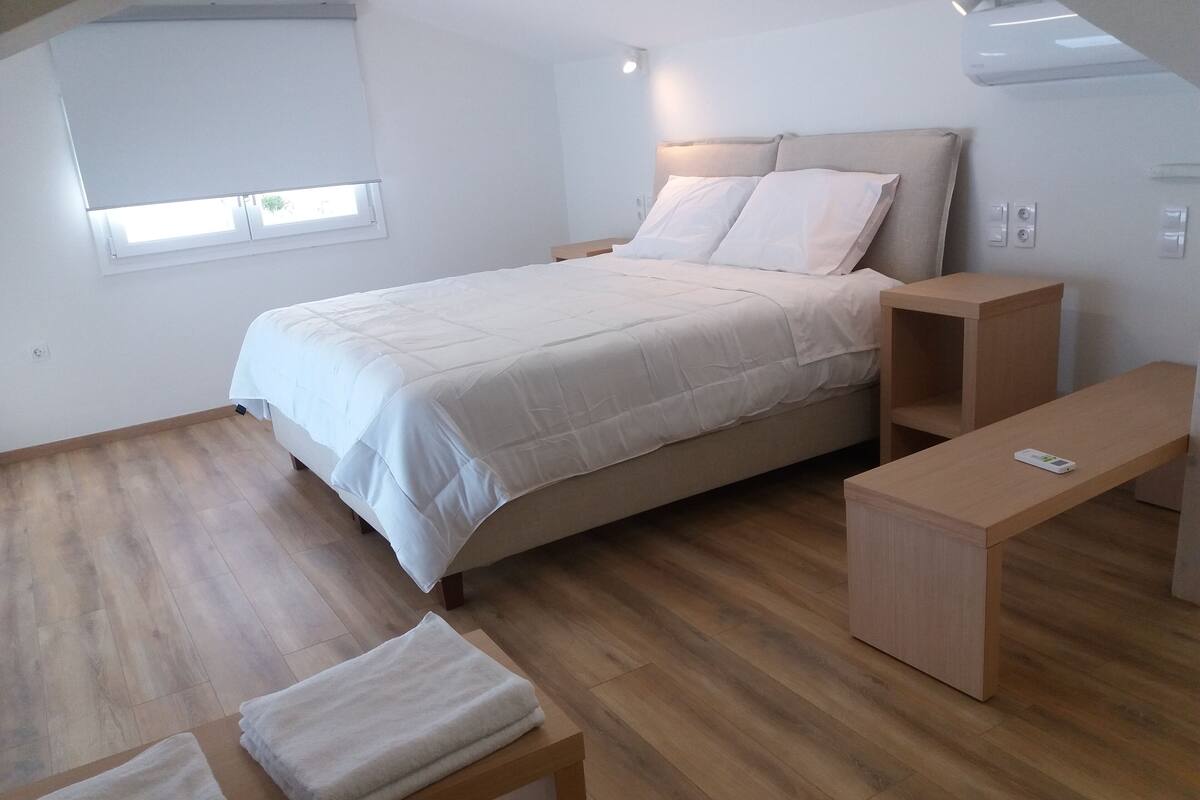 A bedroom with a bed, bedside tables, a bench, and a window.