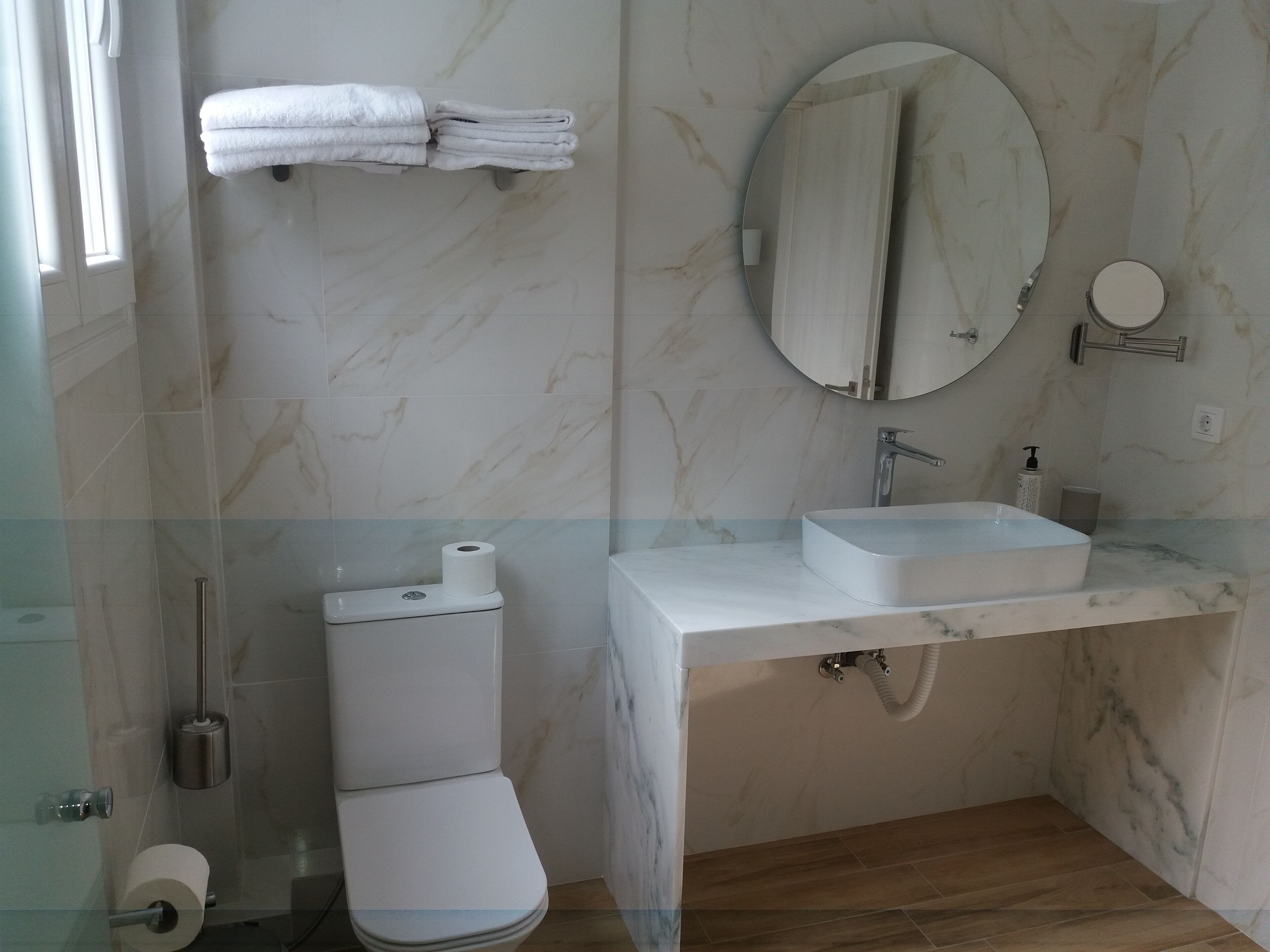 A bathroom with a toilet, a sink, a mirror, and a towel rack.