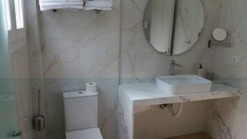A bathroom with a toilet, a sink, a mirror, and a towel rack.