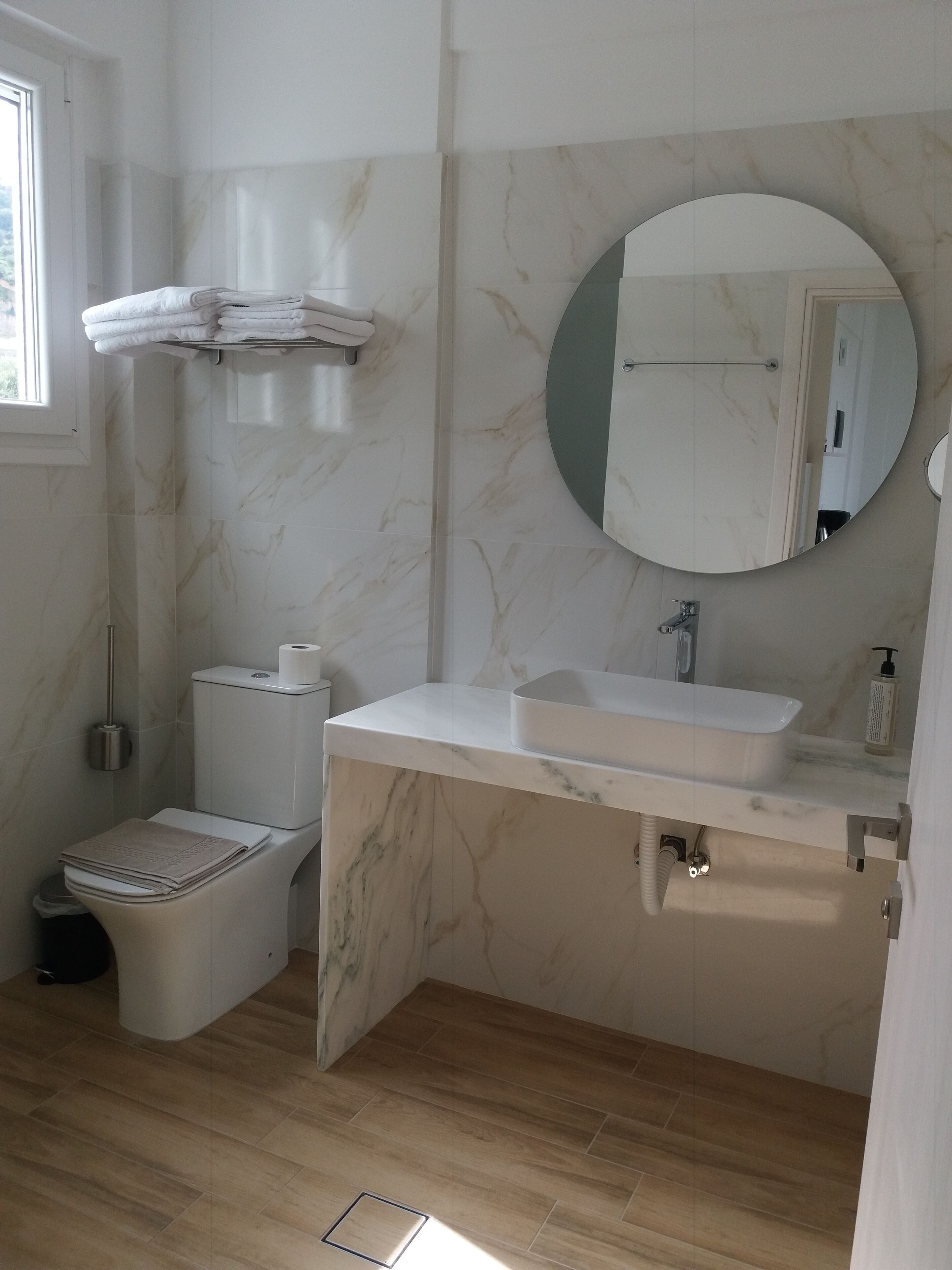 A bathroom with a toilet, sink, and mirror.