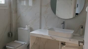Een badkamer met toilet, wastafel en spiegel.