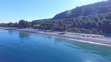 Trên bãi biển, cát trắng, ghế dài tắm nắng, dù trên bãi biển