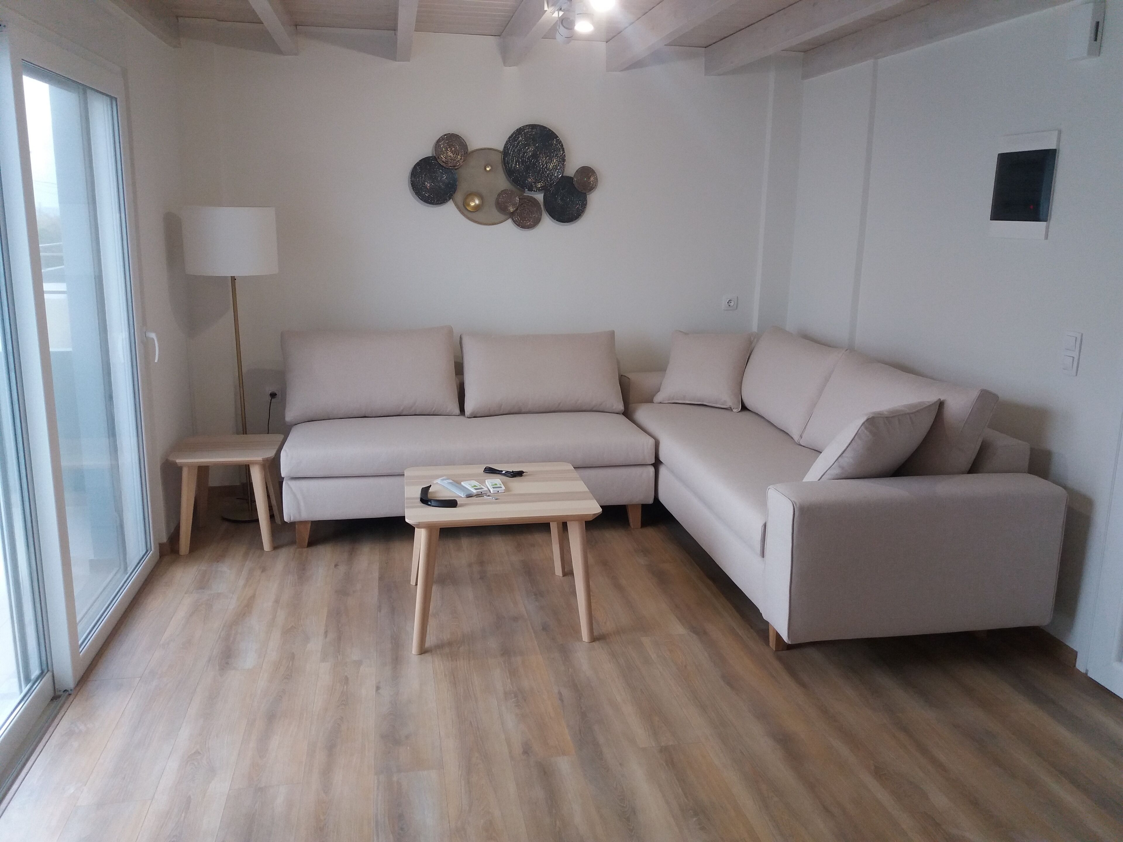 A modern living room with a beige sectional sofa, a wooden coffee table, and a floor lamp.