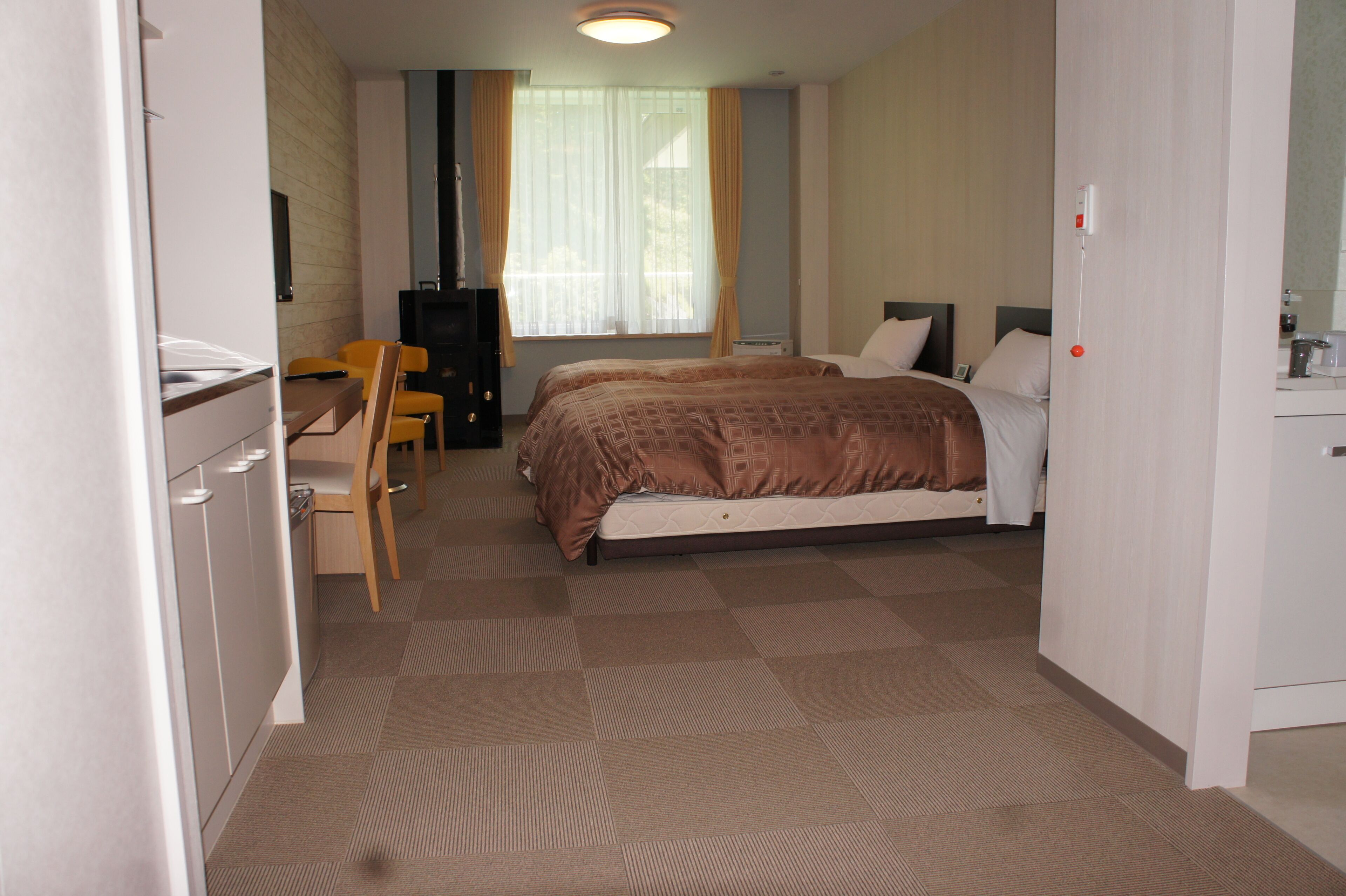 A hotel room with a bed, a desk, a chair, a television, and a window with curtains.