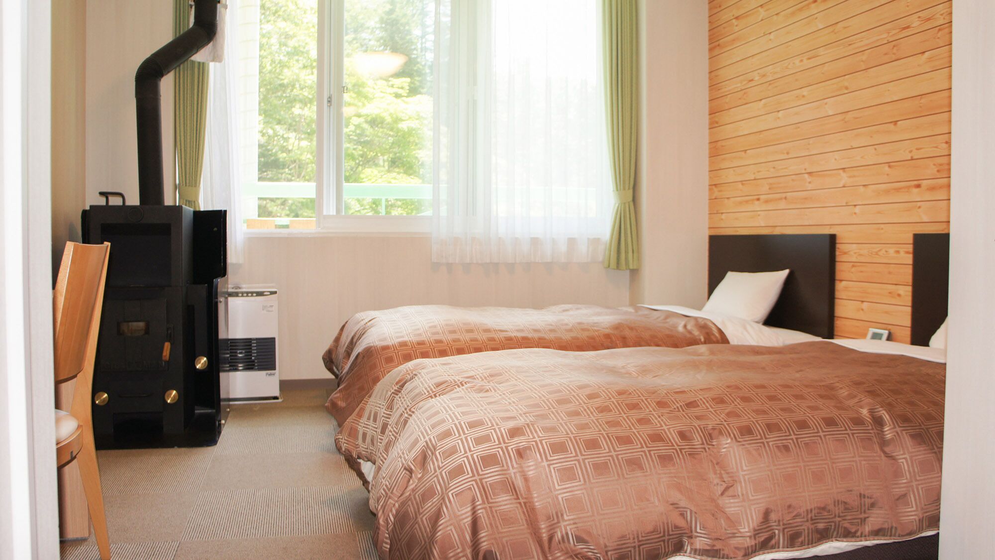 Habitación de hotel con dos camas, un escritorio, una silla, un calentador y una ventana con cortinas.